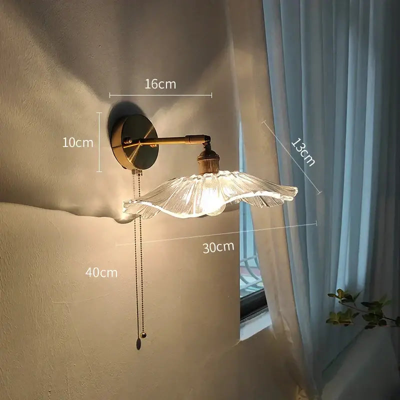 Modern gold wall light with brass arm and translucent glass shade featuring a pull chain for bedroom use