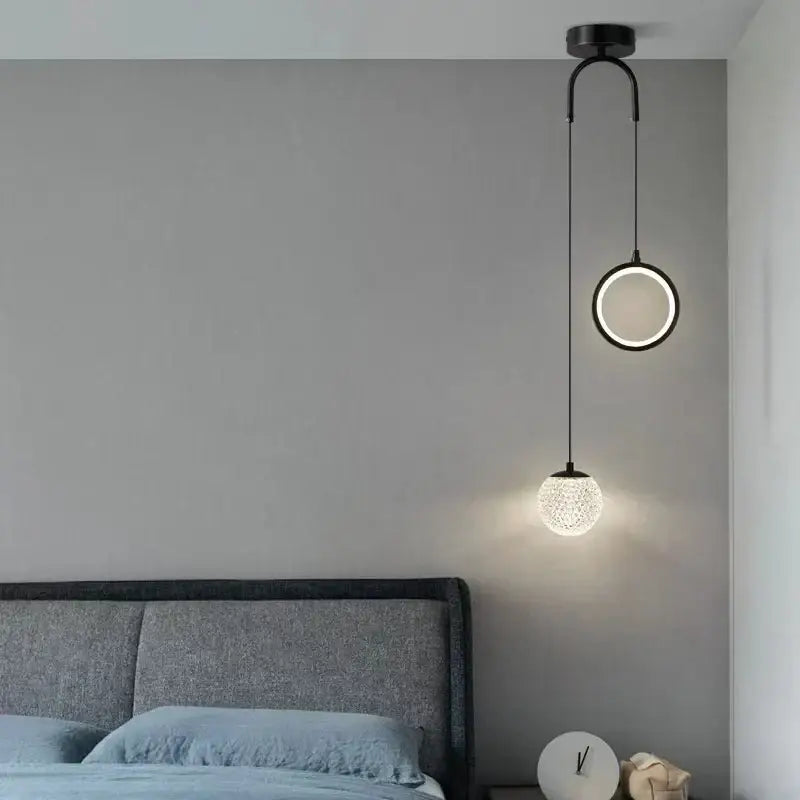 Modern black pendant lights with glass starry led textured globe shades hang above the bedroom bed