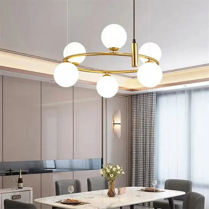 Modern gold globe pendant light chandelier with five frosted glass globes arranged in a circular pattern for dining room use