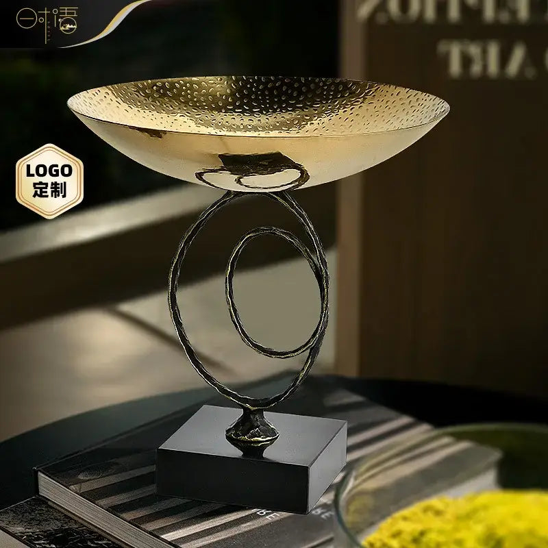 Modern gold hammered metal fruit bowl tray with sleek black base and intertwined circular stand for dining room use