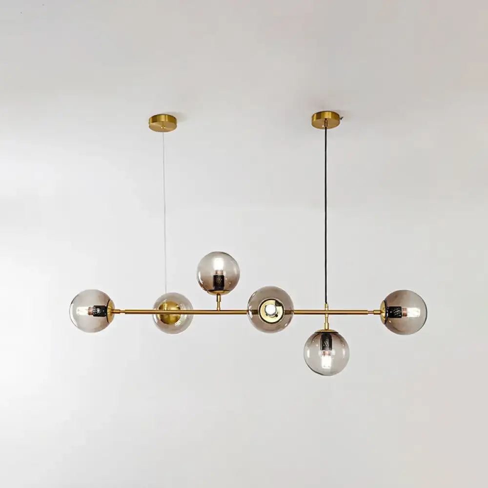 Modern gold island pendant light with five smoked glass globe bulbs in brass for dining room illumination