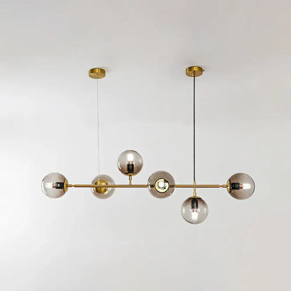 Modern gold island pendant light with five smoked glass globe bulbs in brass for dining room illumination