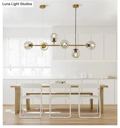 Modern gold island pendant light featuring five spherical glass globes and exposed bulbs for dining room use