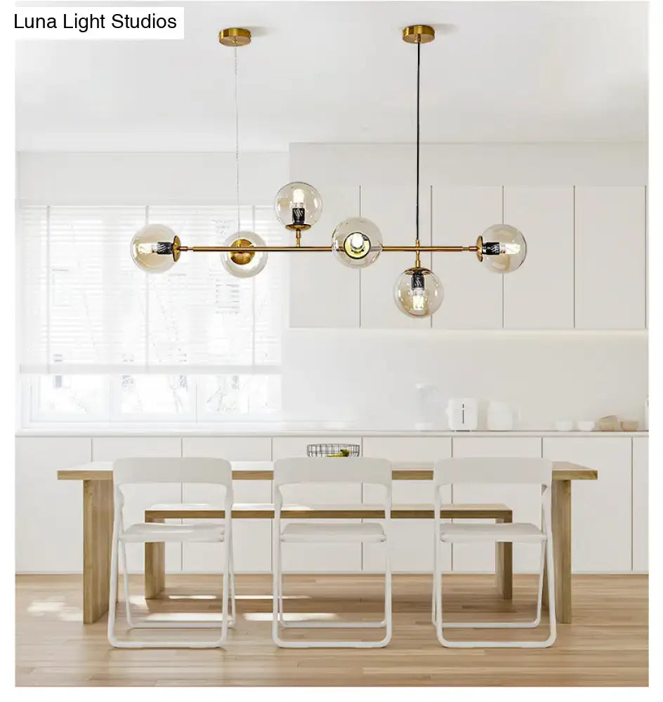 Modern gold island pendant light featuring five spherical glass globes and exposed bulbs for dining room use