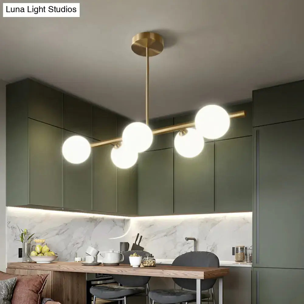 Modern brass island pendant lighting with five spherical glass globes for dining room illumination