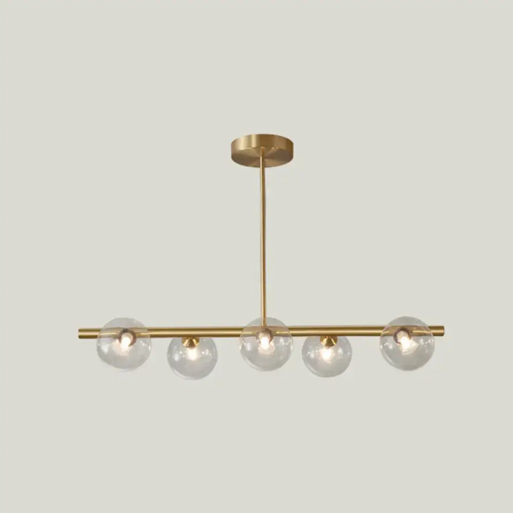 Modern gold island pendant lighting with five clear glass globe shades in brass for dining room pendant lighting