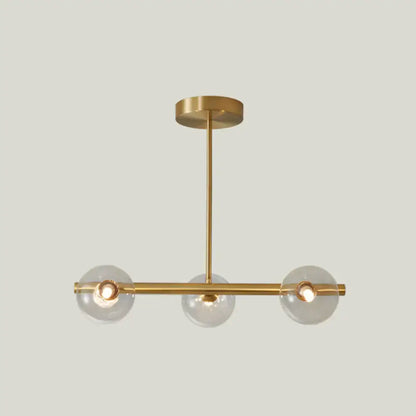 Modern gold island pendant lighting with three clear glass globe shades and minimalist metal arms for dining room