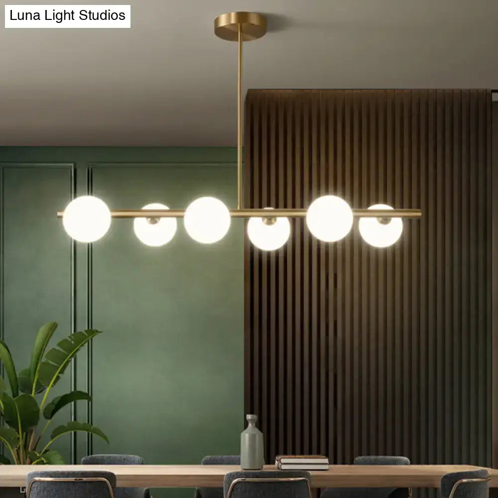 Modern gold brass island pendant lighting with five frosted glass globe shades for dining room illumination
