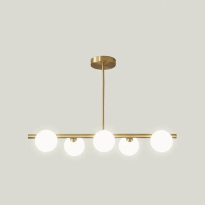 Modern gold island pendant lighting featuring brass linear design with five frosted glass globe bulbs for dining room