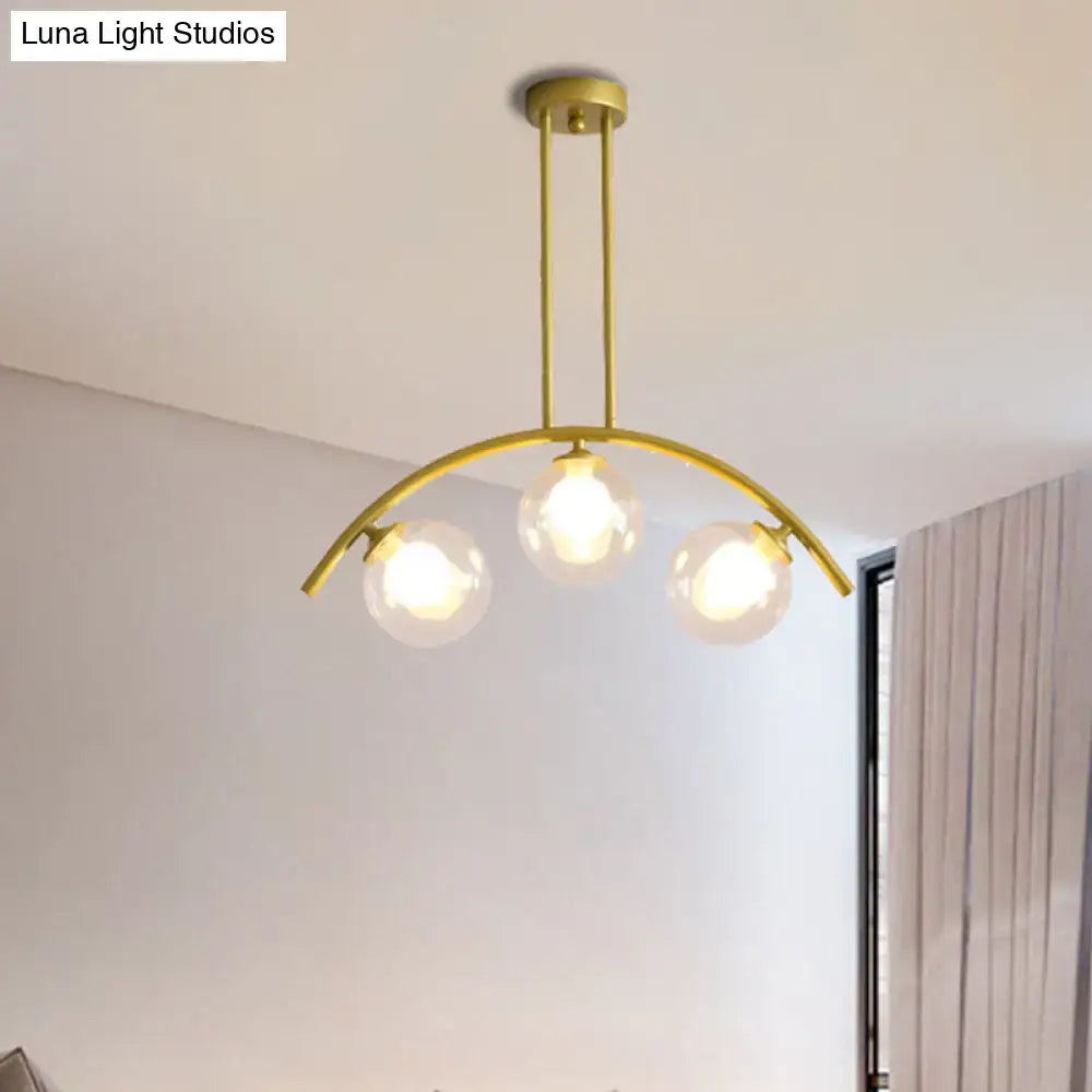 Gold-toned modern DecorBites island pendant with clear white shade and three glass globe bulbs suspended from curved metal arch