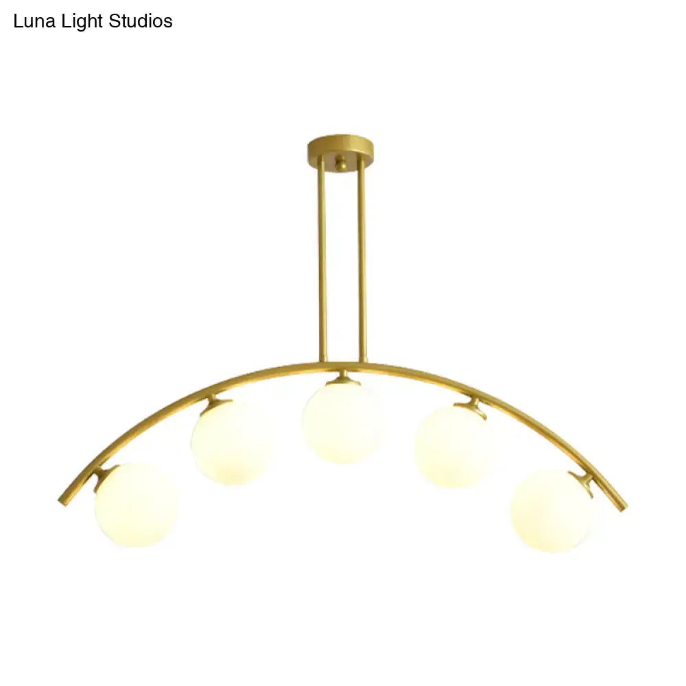 Gold-toned DecorBites island pendant with five frosted globe bulbs and clear white shade for modern kitchens