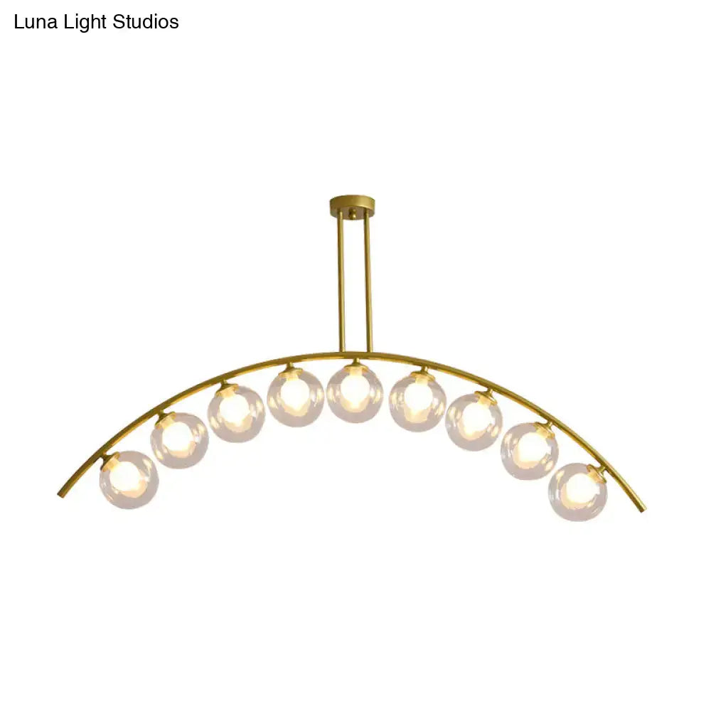 Gold-toned decorbites island pendant with nine spherical glass bulbs and clear white shade for modern kitchens