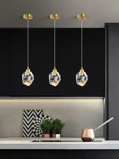 Three modern gold k9 crystal pendant lights with gold-toned fixtures provide warm light 3200k in a kitchen setting