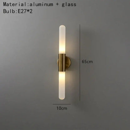 Modern gold led sconce with clear white glass frosted cylindrical shades and brass-finished aluminum mounting base for bedroom wall light