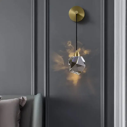 Modern gold led wall sconce with crystal pendant featuring irregular clear glass shade and black cord for living room lighting