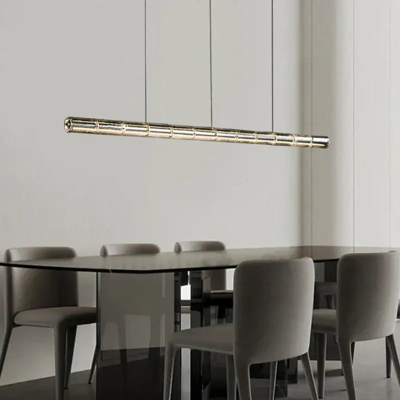A modern gold linear glass led chandelier with a metallic finish and segmented design hangs over a kitchen island