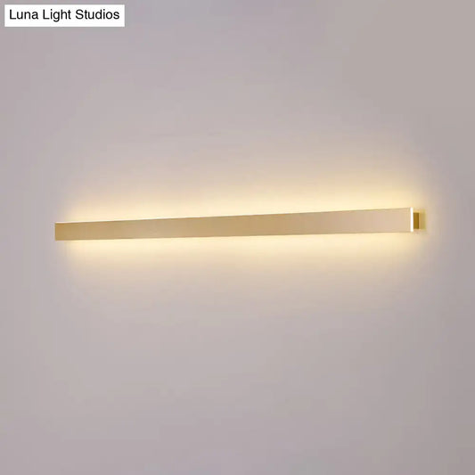 Modern gold linear wall light fixture with a sleek rectangular design emitting warm ambient stairway illumination