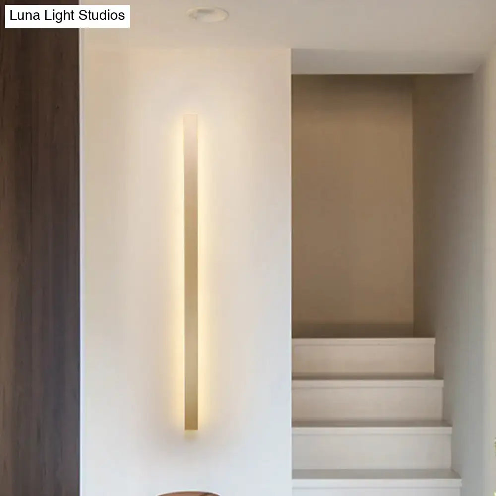 Modern gold linear wall light fixture with a slim vertical design and warm golden glow for stairway ambient lighting