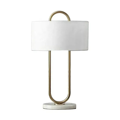 A modern gold luxury led table lamp with white cylindrical shade and u-shaped metal frame on marble base