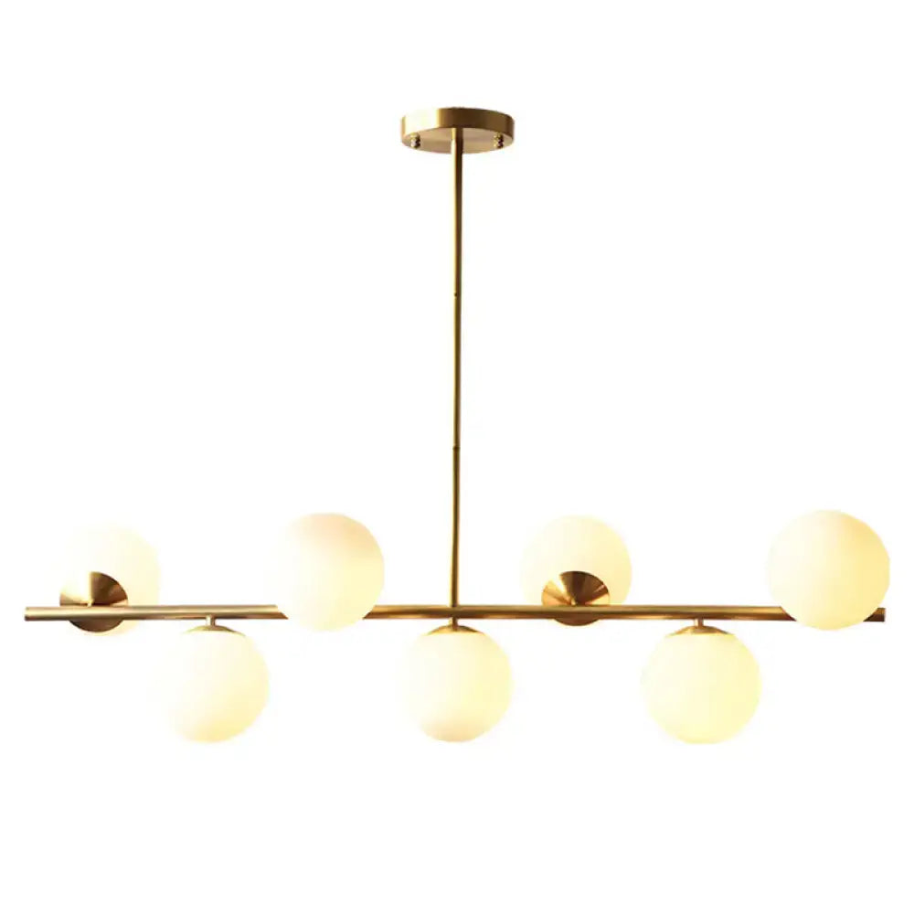 Modern gold metal island pendant dining room chandelier with six frosted white glass globe shades in linear design