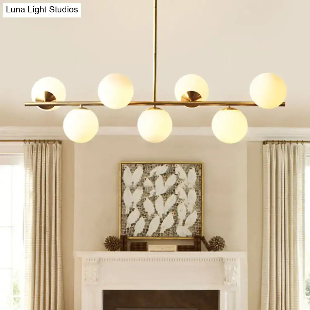 Modern gold metal island pendant chandelier with six frosted white glass globe shades in brass finish for dining room