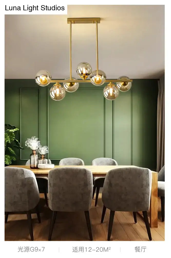 Modern gold metal dining room island light with seven spherical amber glass globes suspended from a sleek bar