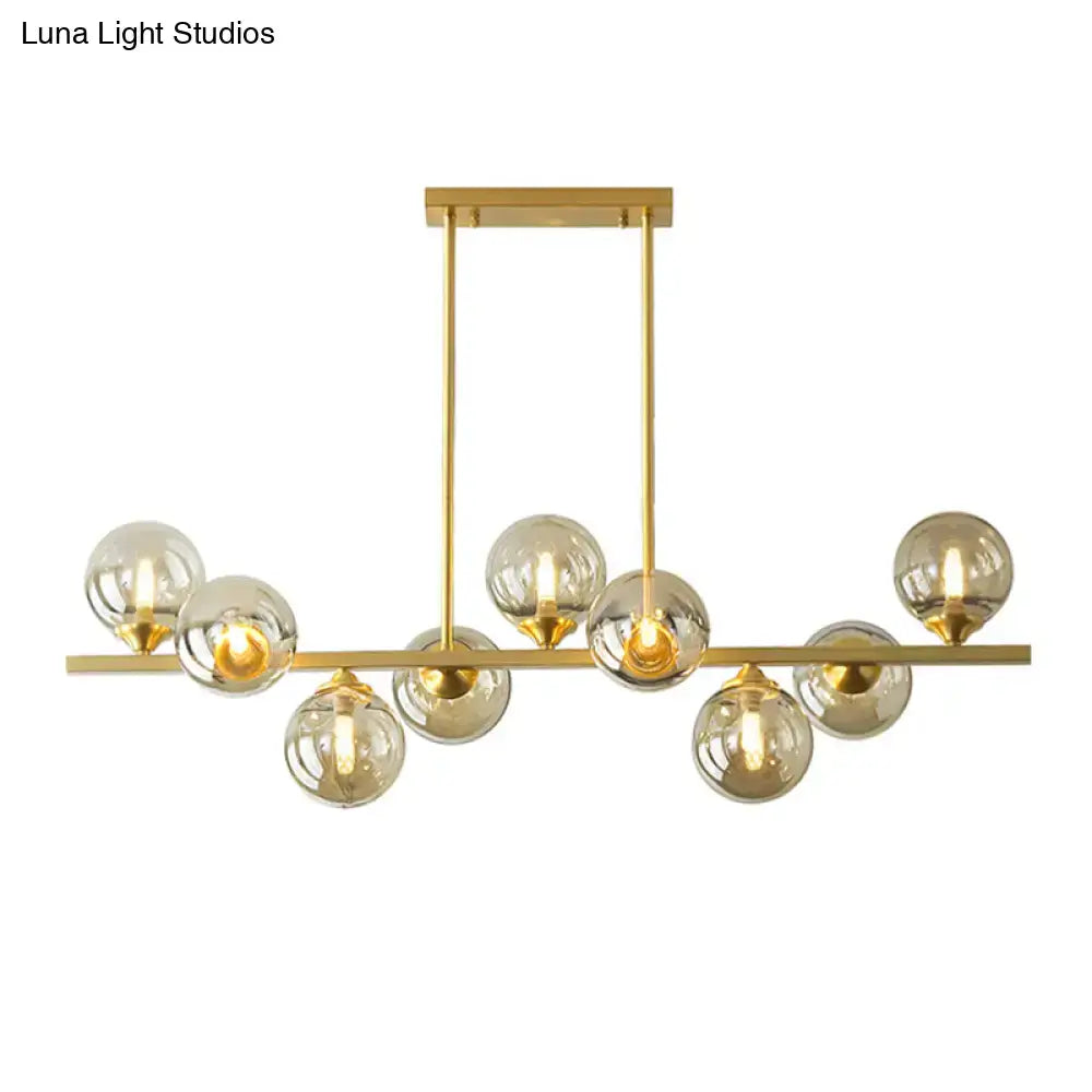 Modern gold metal chandelier with multiple spherical amber glass bulbs for dining room island lighting
