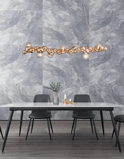 Modern gold metal arched ceiling light with six spherical bulbs in an elongated cluster for dining room use