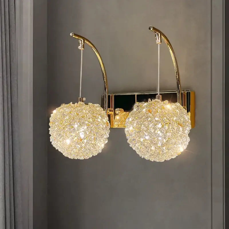 Modern gold metal crystal wall light bedroom sconce with gold-toned curved arms and two spherical crystal chandeliers
