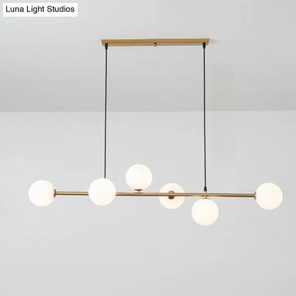 Modern gold metal island pendant with five frosted glass globe bulbs on black cords suspended from wooden mount