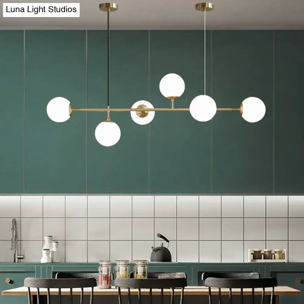 Modern gold metal island pendant with five frosted glass globe bulbs and blue glass spheres for dining rooms