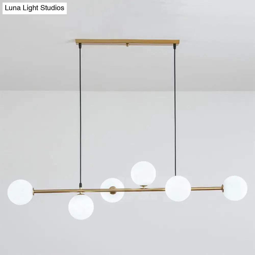 Modern gold metal island pendant with five frosted glass globes and black cords for dining room lighting