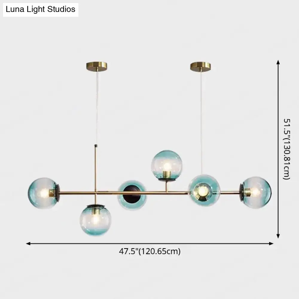 Modern gold metal island pendant with brass frame and translucent teal glass spheres for dining room lighting
