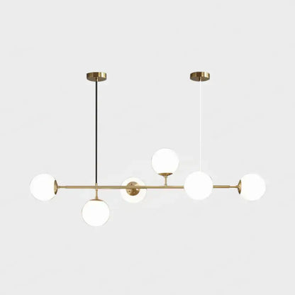 Modern gold metal island pendant light with five frosted glass globes on a horizontal bar for dining room use