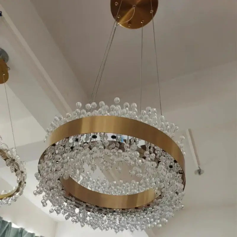 A modern gold metal led chandelier with circular frame and cascading clear crystal beads for dining room decorbites gold metal