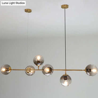Modern gold metal pendant lighting with six smoked glass globe bulbs suspended by black cords for dining room use