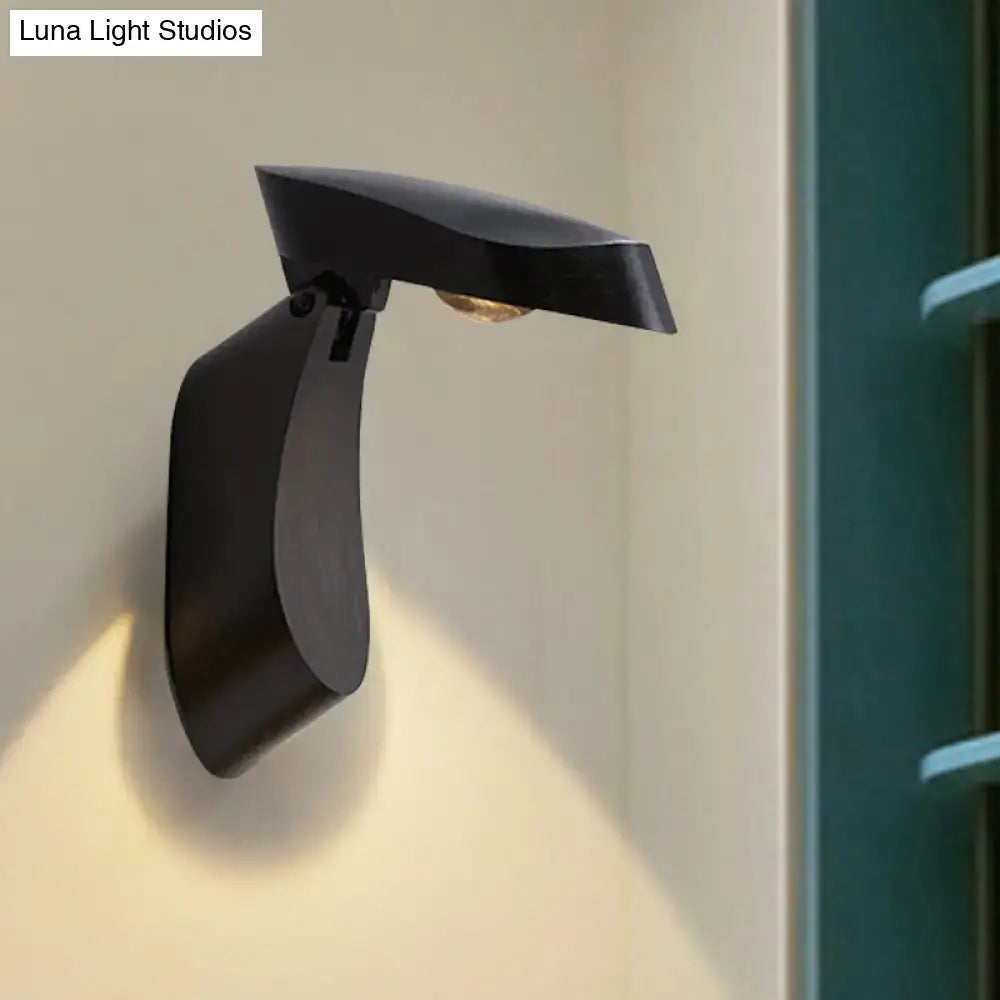 Modern black metal wall light with a sleek curved design and matte finish for bedroom bedside use