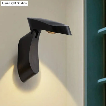 Modern black metal wall light with a sleek curved design and matte finish for bedroom bedside use