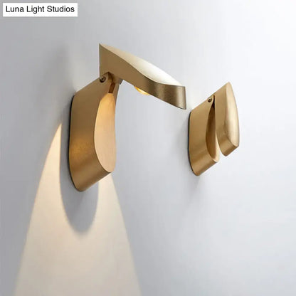 Modern gold metal wall light bedside fixture with minimalist sculptural design and warm light beam