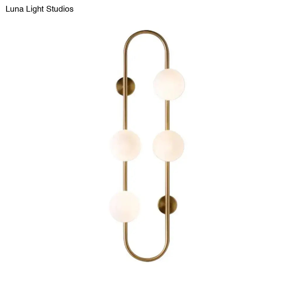 Brass-finished wall light with three frosted milky glass shade globes arranged in a vertical curved design for bedroom use