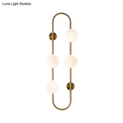 Brass-finished wall light with three frosted milky glass shade globes arranged in a vertical curved design for bedroom use