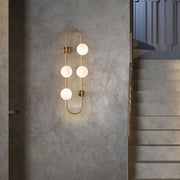 Modern gold wall light with five frosted milky glass shade globes in a vertical curved design for bedroom use