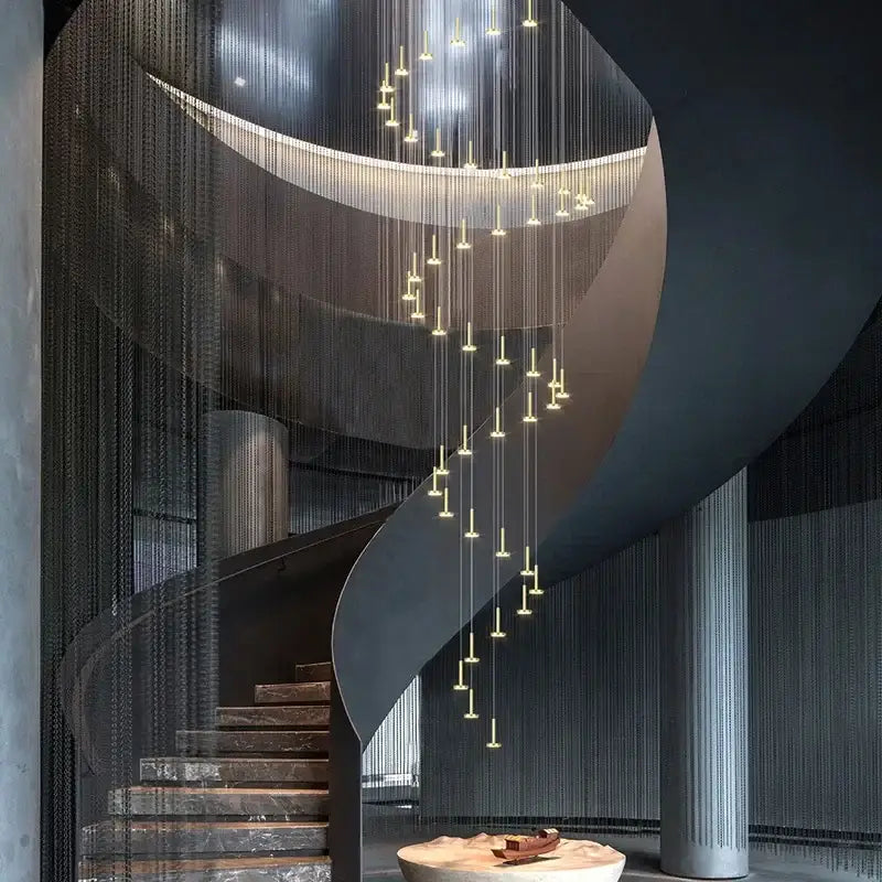 A modern gold minimalist ceiling chandelier with slender lights illuminates a curved staircase with marble steps and dark railings