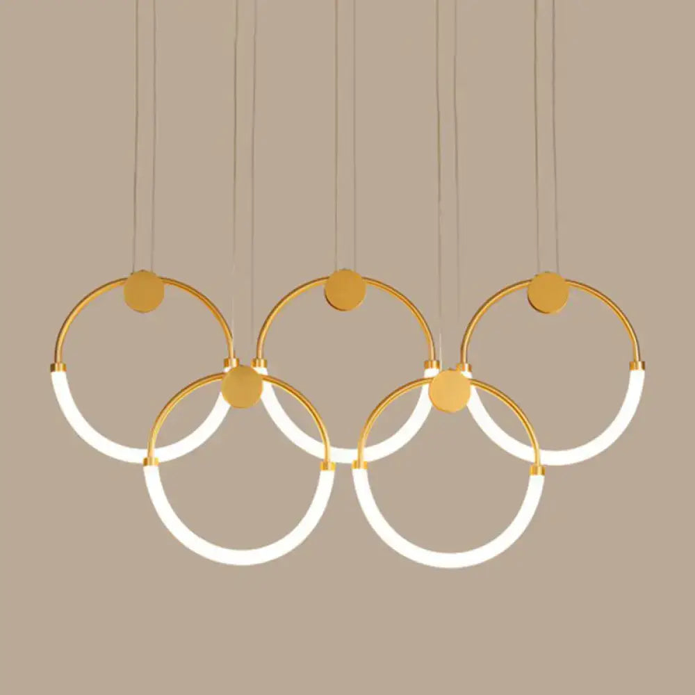Modern gold minimalistic ring pendant light with five interlocking illuminated rings for living room use
