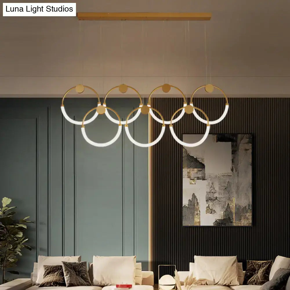 Modern gold minimalistic ring pendant light with illuminated white rings suspended from wooden bar for living room