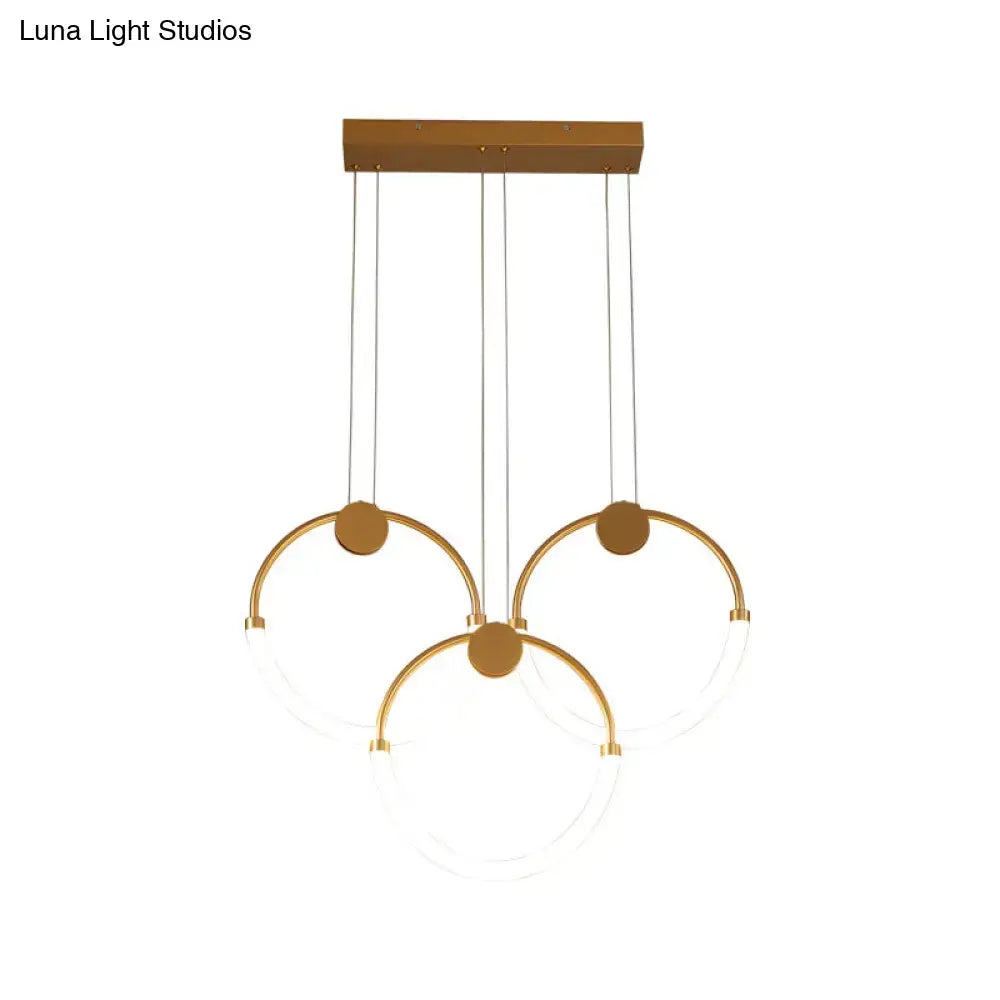 Modern gold minimalistic ring pendant light with three interlocking circular rings and clear glass panels for living room