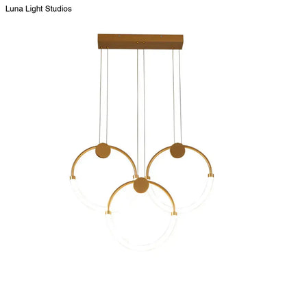 Modern gold minimalistic ring pendant light with three interlocking circular rings and clear glass panels for living room