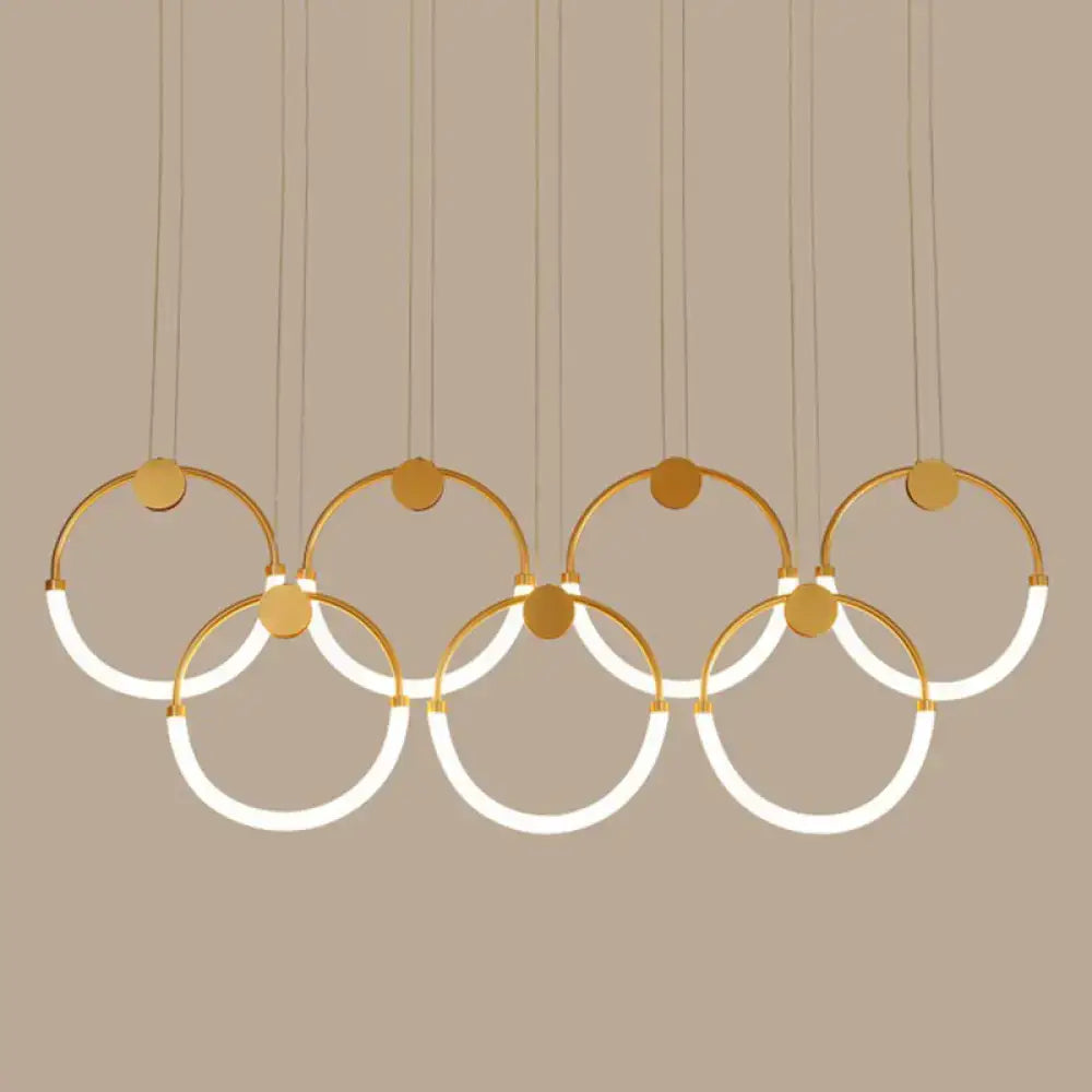 Modern gold-toned minimalistic ring pendant light featuring interlocking circular rings with integrated LED lighting for living room