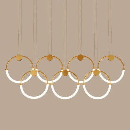 Modern gold-toned minimalistic ring pendant light featuring interlocking circular rings with integrated LED lighting for living room