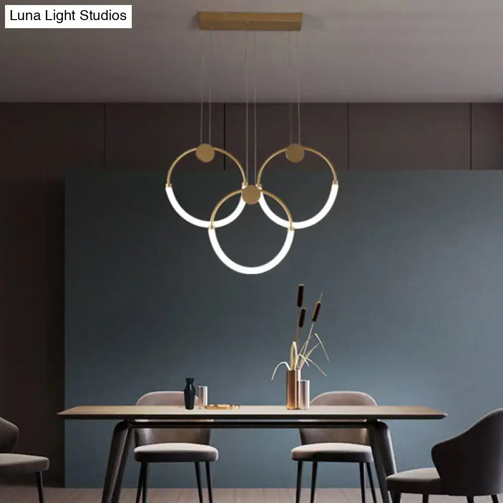 Modern gold minimalistic ring pendant light with illuminated rings suspended from wooden ceiling fixture for living room
